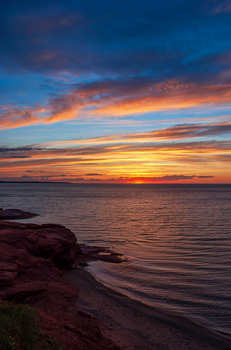 Colorful sunset above rippled waters. Dramatic sky in red and orange shades. Gulf of St. Lawrence, Atlantic Ocean. Oceanview Lookoff, Cavendish Beach.