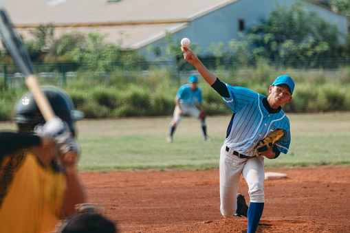 The pitcher throws the ball towards the catcher according to the tactical strategy, while the batter prepares to hit it.