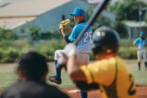 Shot of a young man pitching a ball during a baseball match