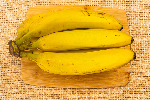 Bunch of bananas in a wooden bowl on a kitchen counter.