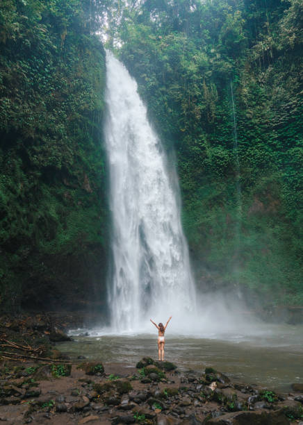 istock Woman standing near the refreshing waterfall on Bali 2072491031