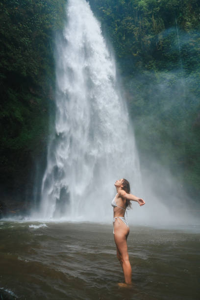 istock Woman standing near the refreshing powerful  waterfall on Bali 2072491056