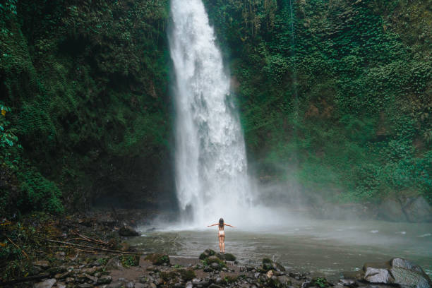 istock Woman standing near the refreshing waterfall on Bali 2072491575