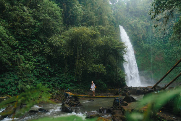istock Woman standing near the refreshing waterfall on Bali 2072492658
