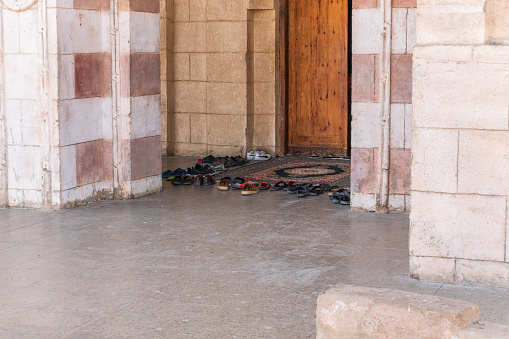 Believers' shoes left in front of the entrance to the Muslim mosque. Footwear of prayers left in front of a mosque