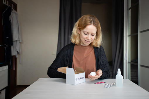 Woman unpacking medications, home pharmacy delivery, online drug order, healthcare