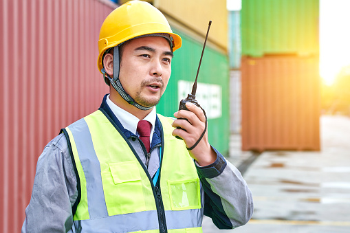 One asian worker using walkie-talkie at commercial dock.