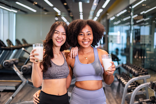 Drinking milk during a workout helps maintain blood pressure. Young woman drinking  milk after exercising or yoga therapy at gym.