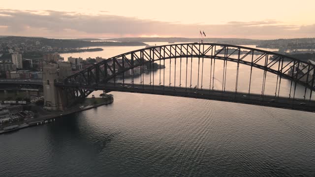 Aerial drone pullback reverse flyover view of Sydney Harbour Bridge, NSW Australia during an early morning sunrise in March 2024