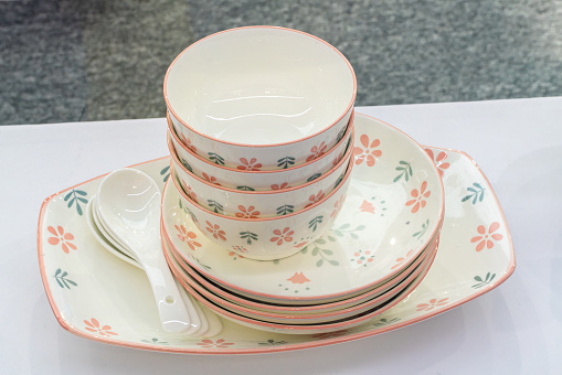 Stack of various English vintage porcelain teacups with floral decoration on dark background.
