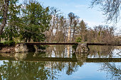 Pond with small bridge above with trees around and Minaret building on the background in Lednicko-valticky areal in Czech republic