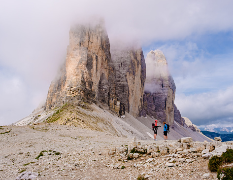Tre Cime di Lavaredo peaks or Drei Zinnen at sunset, Dobbiaco Toblach, Trentino -Alto Adige or South Tyrol, Italy. Europe Alps. A couple of man and woman hiking in the Dolomites July 2021