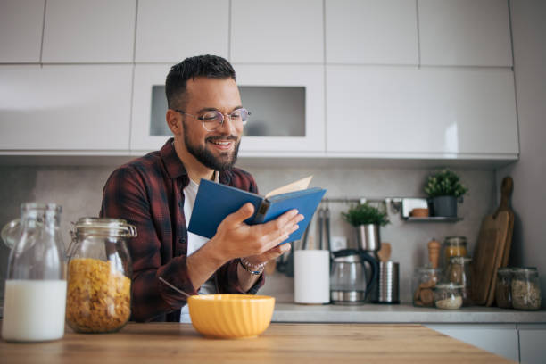 istock A man is sitting in the kitchen and reading a book. 2072687451