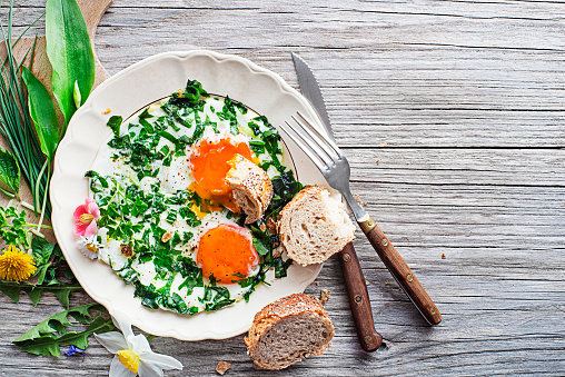 Fried eggs with fresh spring plants and herbs. Healthy spring diet food concept.