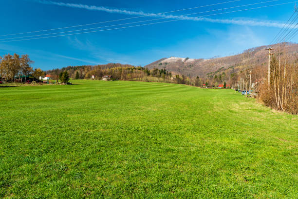 Early springtime above Celadna village in Czech republic with fresh green meadow with hills covered by bit of snow above