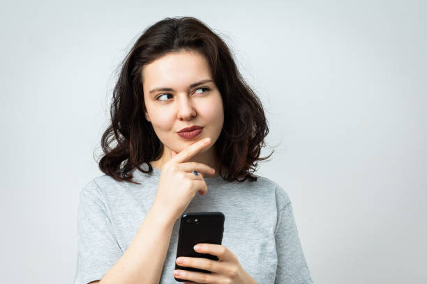 istock Beautiful young girl with phone looking aside 2072722853