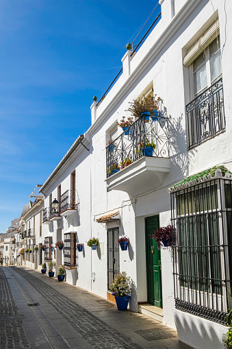 Alley lined with traditional whitewashed houses in the historic centre of Mijas, one of the most beautiful towns in Andalusia, where the walls are decorated with flower pots