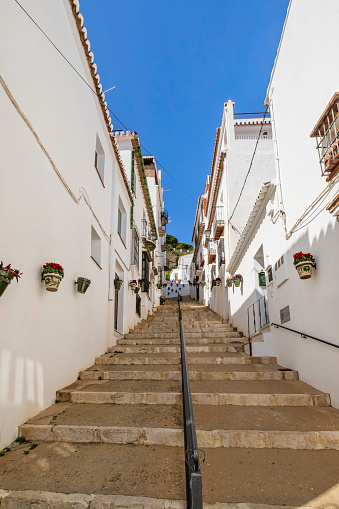 Alley lined with traditional whitewashed houses in the historic centre of Mijas, one of the most beautiful towns in Andalusia, where the walls are decorated with flower pots