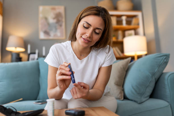 istock Blood sugar testing at home. Checking Blood Sugar Level At Home. Diabetic Checking Blood Sugar Levels. Woman checking blood sugar level by glucometer and test stripe at home 2072778131