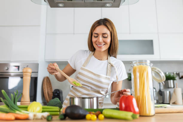 istock Joyful Young Lady Cooking and Sampling Dinner in a Pot, Present in a Contemporary Home Kitchen. Homemaker Preparing Nutritious Meal with a Smile. Domestic Life and Nourishment. Healthy Eating. 2072778650