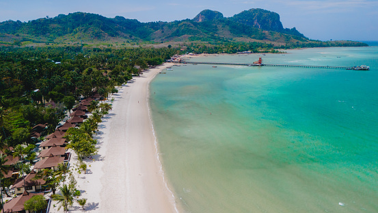 Drone aerial view at Koh Muk a tropical island with palm trees and soft white sand, and a turqouse colored ocean in Koh Mook Trang Thailand