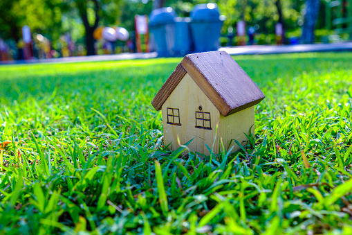 Wooden house toy on greenmeadow grass real etate business industry concept