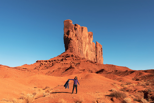 A woman standing in front of famous red rocks of Monument Valley. Navajo Tribal Park landscape, Utah/Arizona, USA