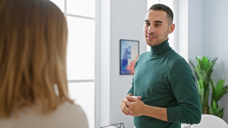 A man and woman engage in a discussion in a bright, modern office setting, illustrating workplace communication.