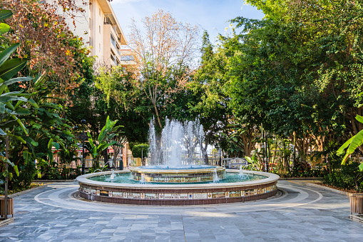 A 18th-century fountain stands out in the Parque de la Alameda in Marbella, a public garden with a number of trees, stone benches and paths