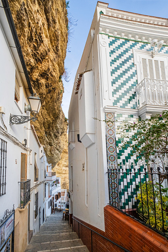Glimpse of Setenil de las Bodegas, a town along the narrow river gorge of the Rio Trejo with some houses being built under or into the rock walls of the gorge itself
