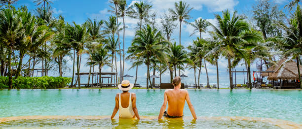 istock A couple relaxing in a pool, palm trees all around them under the blue sky 2072801900