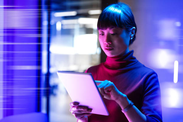 Futuristic office with Asian mature businesswoman using digital tablet in office Futuristic office with Japanese mature businesswoman computer technology people stock pictures, royalty-free photos & images