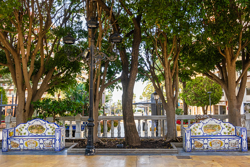 Parque de la Alameda in Marbella, a public garden with a number of trees, benches decorated with ceramic tiles and paths