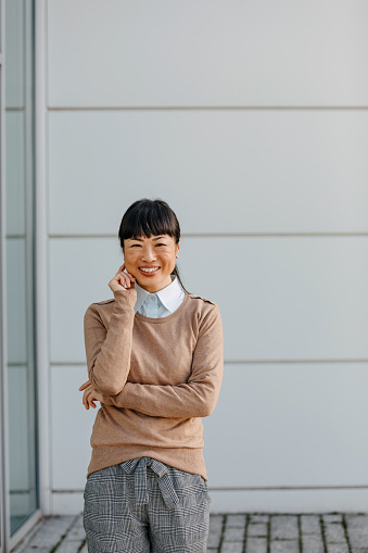 In the bustling heart of the city, a portrait of the mature Chinese businesswoman in front of a business building captures the embodiment of professionalism, her image a beacon of strength, intelligence, and grace in the corporate realm