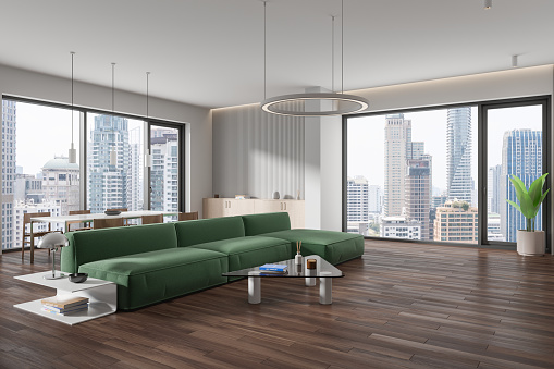 Corner view of home living room interior with soft place, green sofa and eating table with chairs. Modern relax place in apartment with panoramic window on Bangkok skyscrapers. 3D rendering