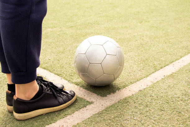 weibliche beine auf einem fußballfeld und ein grauer fußball in der ukraine, fußball spielen im hof - soccer field grass single line lawn stock-fotos und bilder