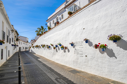 Street lined with traditional whitewashed houses in the historic centre of Mijas, one of the most beautiful towns in Andalusia, where the walls are decorated with flower pots and poems written by local poets