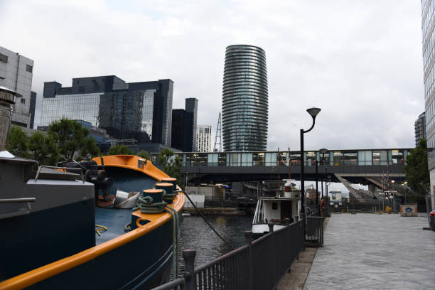 View across Salford Quays in Manchester UK.  Tall modern buildings can be seen. People can be seen on the promenade