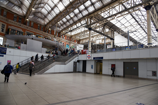 Waterloo station is a central London terminus on the National Rail network in the United Kingdom.  The image shows the main arrival and departure hall with several commuters.