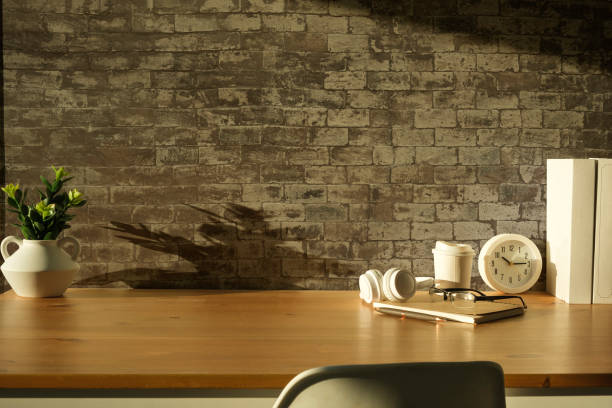 istock Home office interior. Picture frame, coffee cup, notebook and pencil holder on white table against brick wall. Copy space. 2072912521