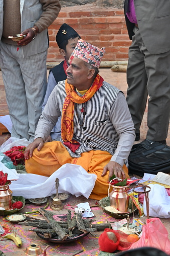 Kirtipur, Nepal - February 12, 2024 - A Newari Wedding starts with the ritual of, the groom side sending twelve areca nut in a huge silver bowl along with fruits, sweets, gold jewelry, clothes and other cosmetic accessories for the bride which are decorated and displayed in trays in an eye-catching way. The groom and the groom’s mother is absent in this ceremony whereas the bride’s mother starts the ceremony by worshipping lord Ganesh, lord of fire(Agni devta) and other god and goddesses. This ritual is usually performed four days before the wedding on the same day as the bride side’s reception party.