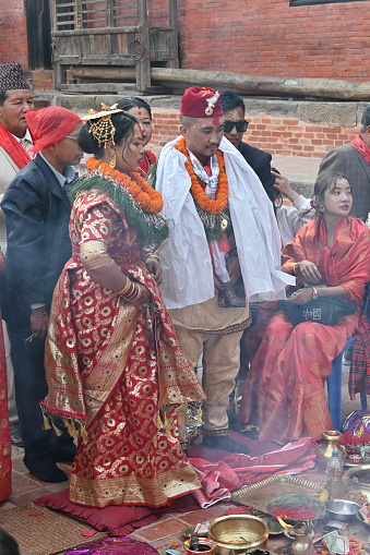 Kirtipur, Nepal - February 12, 2024 - A Newari Wedding starts with the ritual of, the groom side sending twelve areca nut in a huge silver bowl along with fruits, sweets, gold jewelry, clothes and other cosmetic accessories for the bride which are decorated and displayed in trays in an eye-catching way. The groom and the groom’s mother is absent in this ceremony whereas the bride’s mother starts the ceremony by worshipping lord Ganesh, lord of fire(Agni devta) and other god and goddesses. This ritual is usually performed four days before the wedding on the same day as the bride side’s reception party.