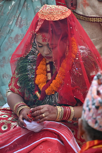 Kirtipur, Nepal - February 12, 2024 - A Newari Wedding starts with the ritual of, the groom side sending twelve areca nut in a huge silver bowl along with fruits, sweets, gold jewelry, clothes and other cosmetic accessories for the bride which are decorated and displayed in trays in an eye-catching way. The groom and the groom’s mother is absent in this ceremony whereas the bride’s mother starts the ceremony by worshipping lord Ganesh, lord of fire(Agni devta) and other god and goddesses. This ritual is usually performed four days before the wedding on the same day as the bride side’s reception party.