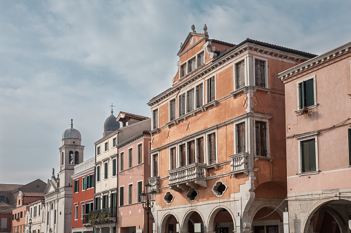 The main street of the old town of Chioggia called Corso del Popolo with historic houses and the St. Francis church, Veneto, Italy