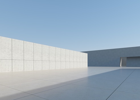 Gray concrete fencing wall with a white modern house facade behind. Pole, cement sidewalk and asphat road in front. Background for copy space.