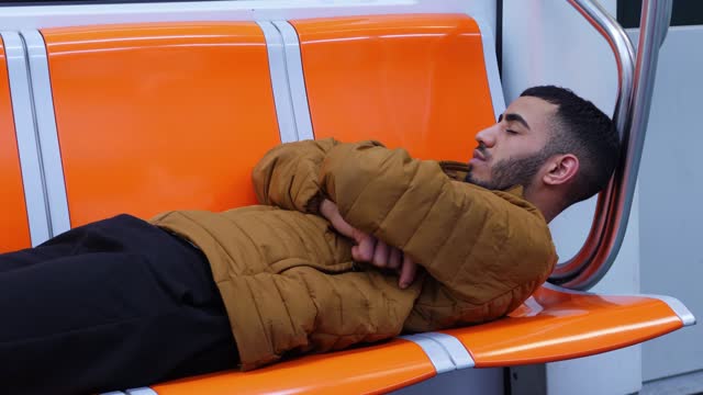 stress, tiderness – young migrant sleeps lying on the seats of the subway