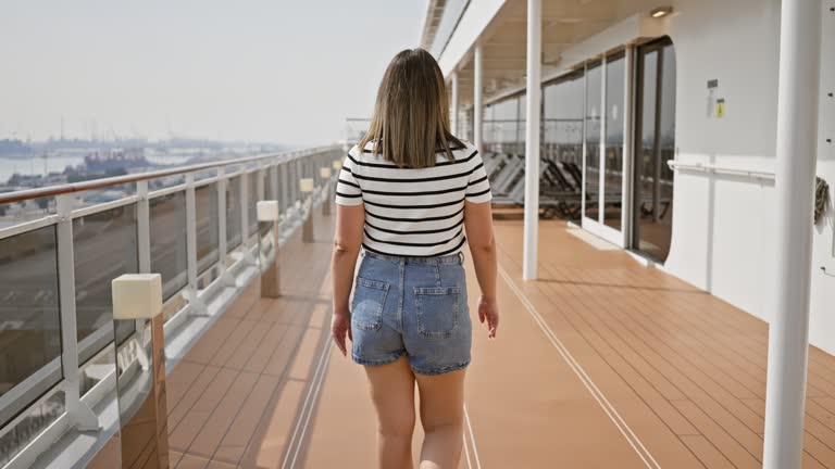 A smiling young woman in casual attire enjoying a sunny day on the promenade deck of a cruise ship.