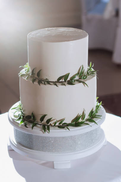 istock a three-tiered white wedding cake decorated with green leaves stands on a table at the entrance to the wedding hall 2073021104