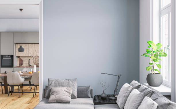 istock A modern home interior: a living room with a grey sofa in front of a white blank wall and a window with a cityscape view in the foreground, a modern light grey kitchen and a full dining table with chairs in the background 2073021282