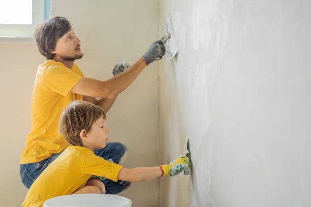 man with his son makes repairs at home, he teaches children to plaster the walls with a spatula in his hands - plaster plasterer work tool child imagens e fotografias de stock